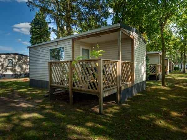 Stacaravan met houten veranda in een bosrijk park