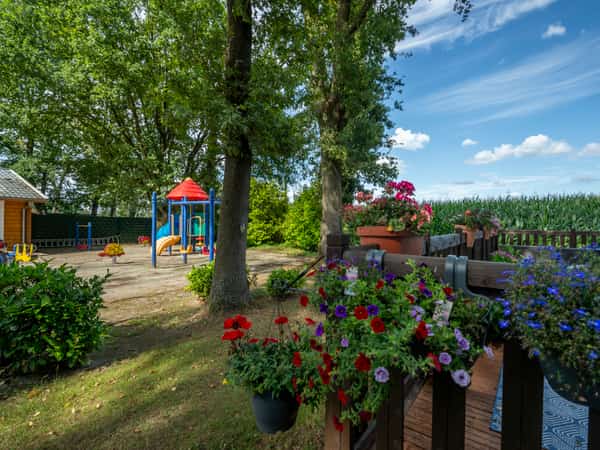 Speeltuin naast terras met bloemen en bomen