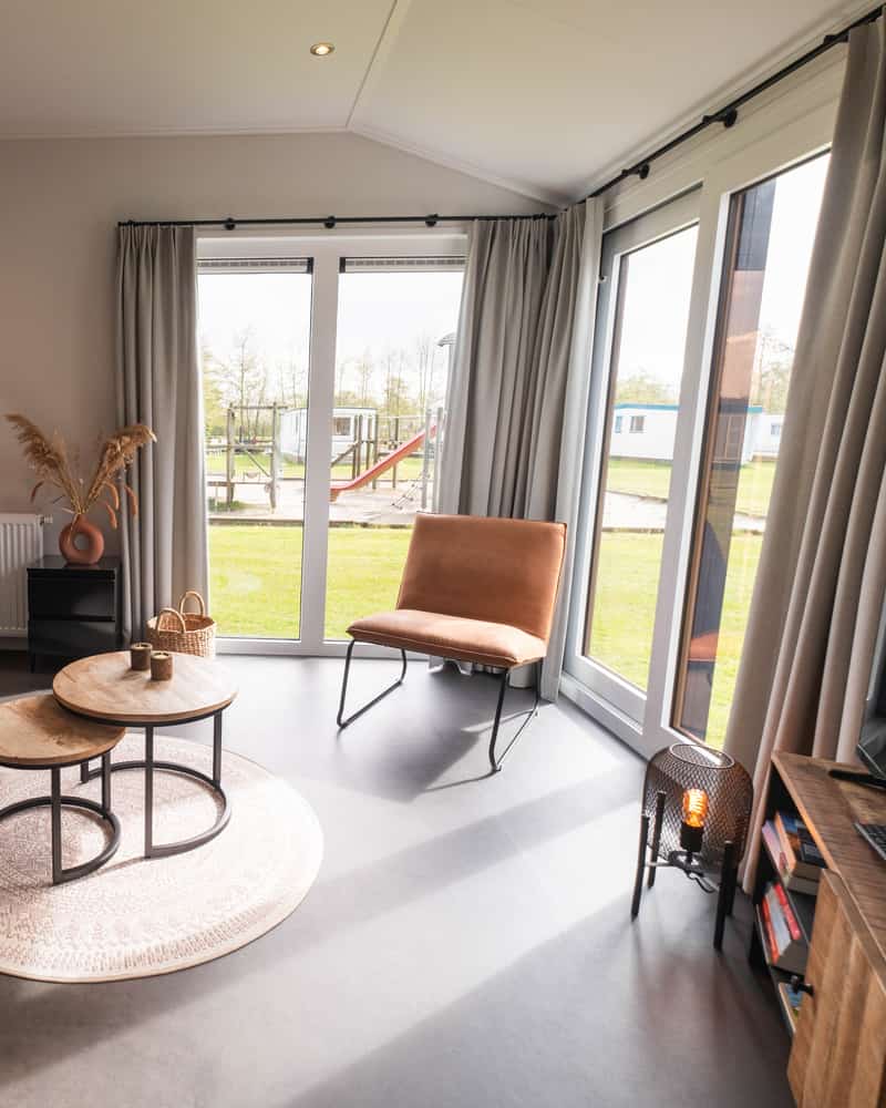 Woonkamer met bank en tuindeuren in Chalet Deluxe Kluut op Camping Cupido