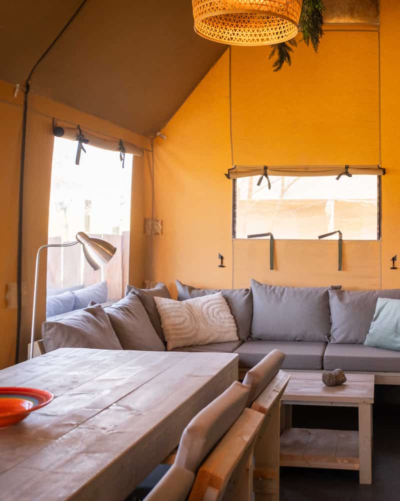 Woonruimte met zithoek en eettafel in een safaritent op Camping Cupido