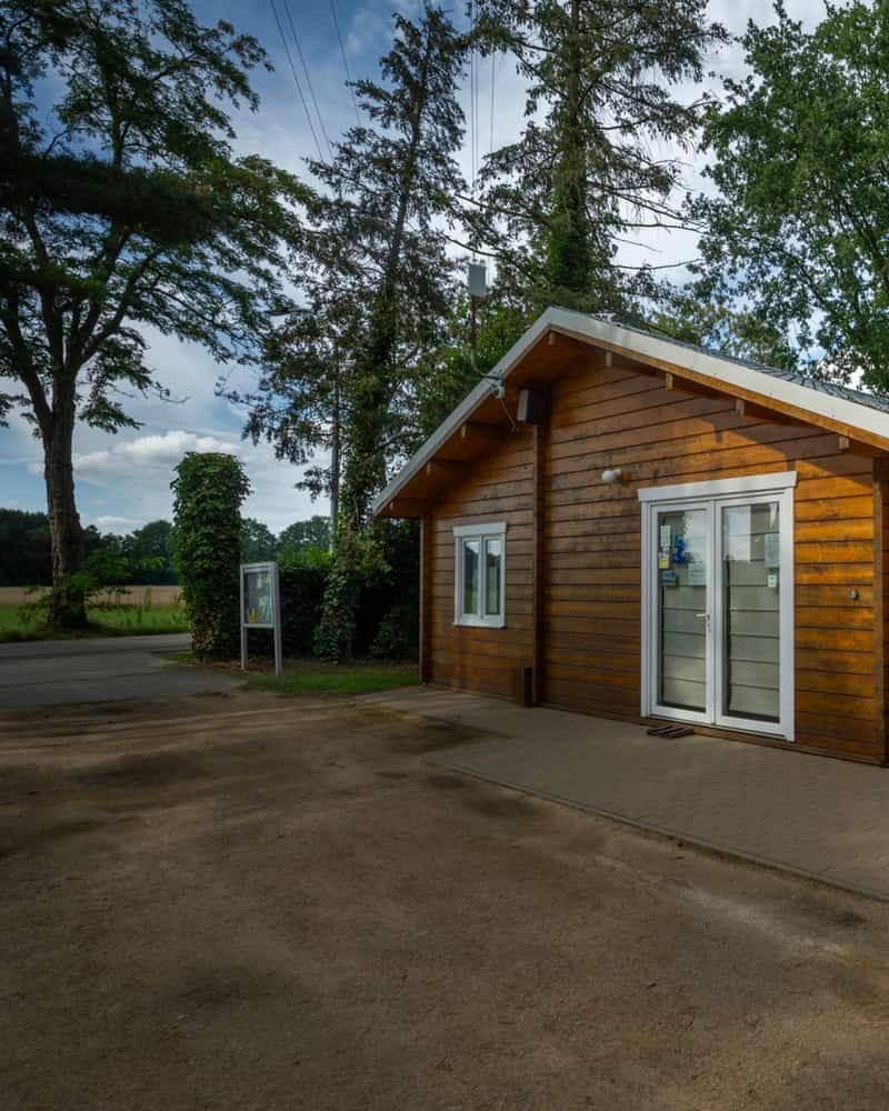 Houten gebouw met speeltoestellen in een bosrijke omgeving