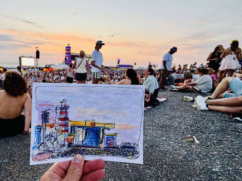 Eigen schets van het podium en de vuurtoren bij Concert at SEA op de Brouwersdam, met het festival bij zonsondergang op de achtergrond