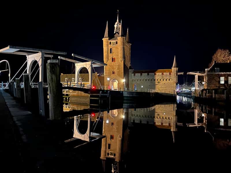 De verlichte Zuidhavenpoort met ophaalbrug, weerspiegeld in de haven bij nacht in Zierikzee, Zeeland