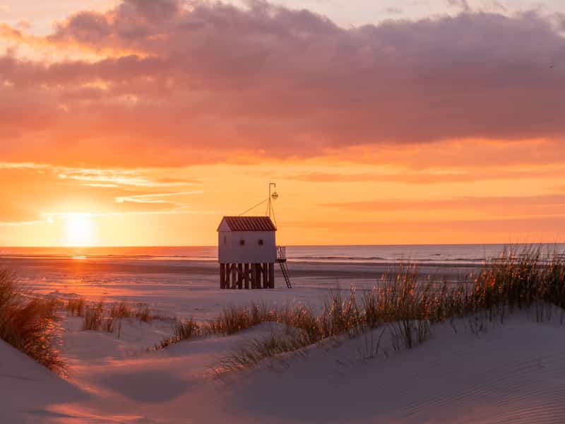 Strandhuisje op palen bij zonsondergang op het strand van Terschelling