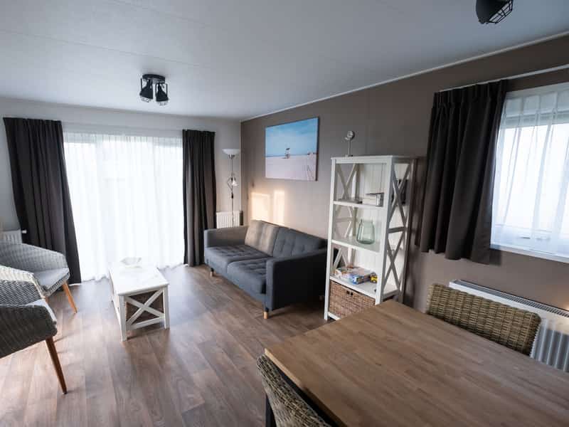 Woonkamer met rieten stoelen, witte tafel en grijze bank